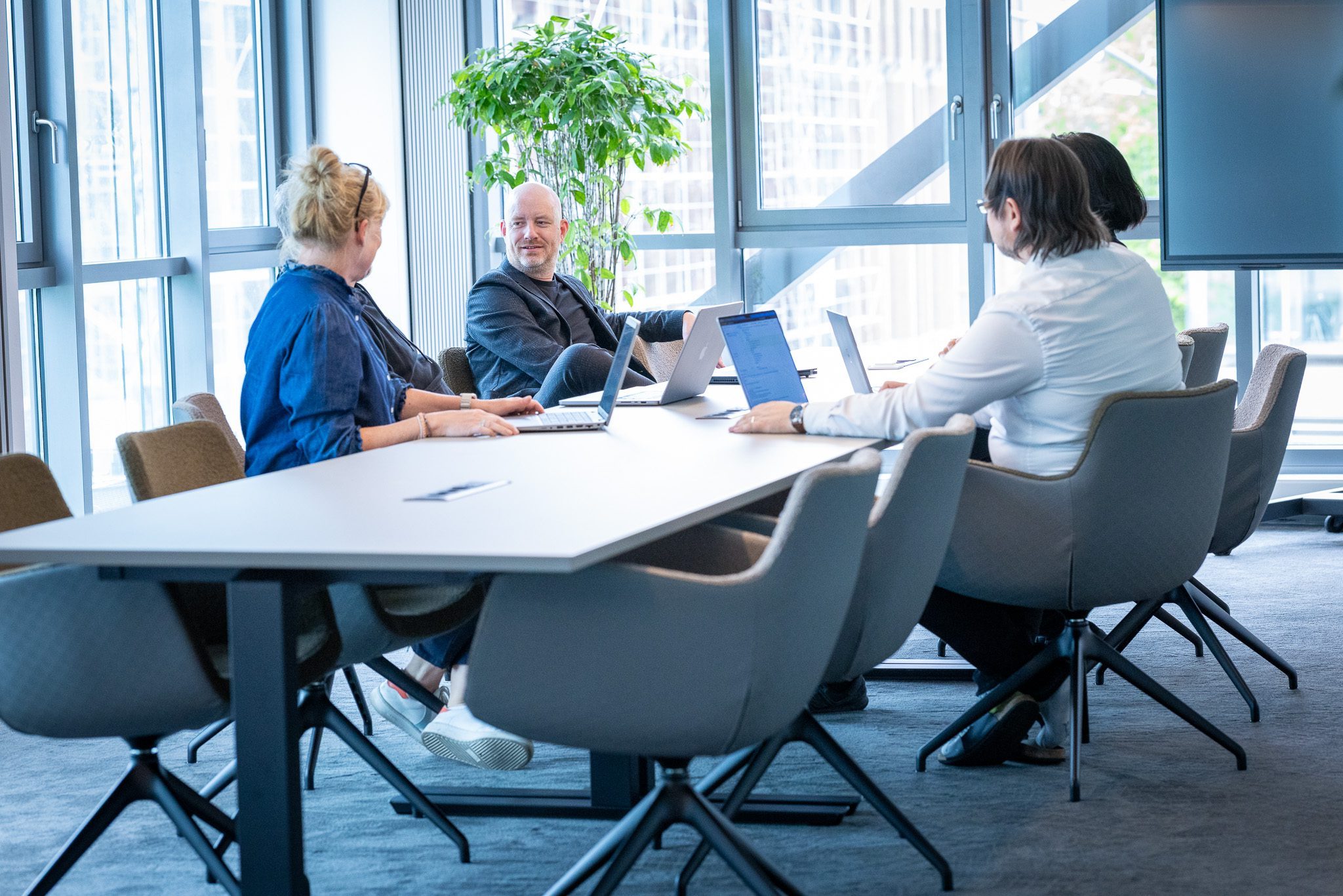 Three people talking with laptops in a modern office