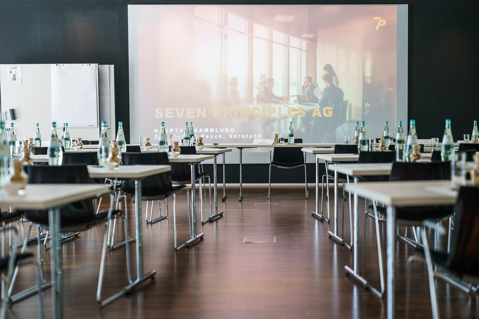 Hall with chairs, tables and a screen, set up for the Annual General Meeting