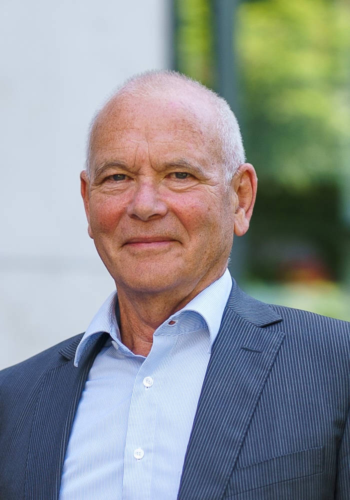 Portrait of an older man in a jacket against a green background