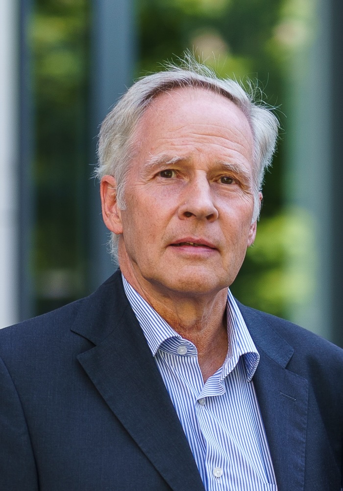 Portrait of an older man in a business suit against a green backdrop
