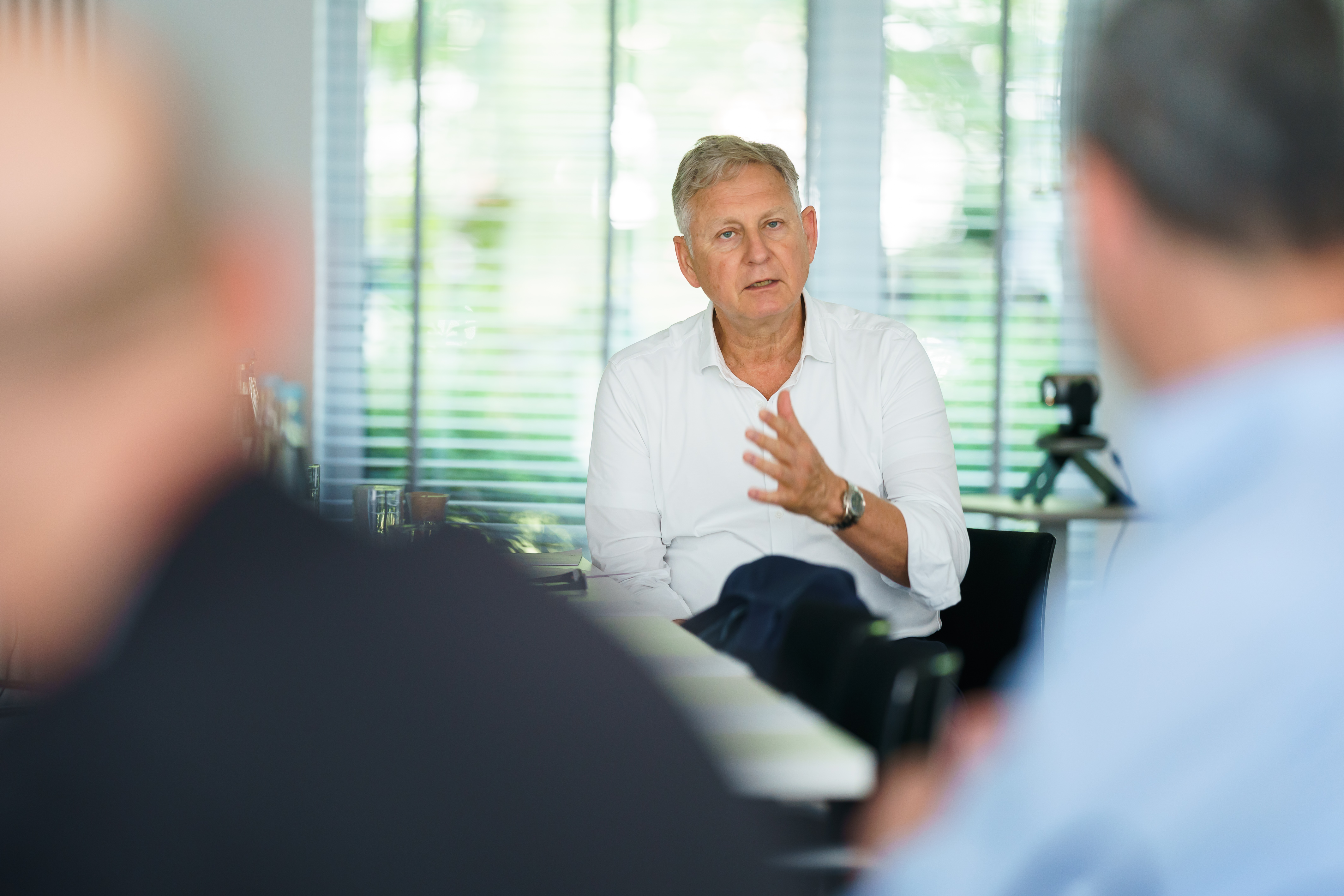 Man in a white shirt talking with two people at a meeting table