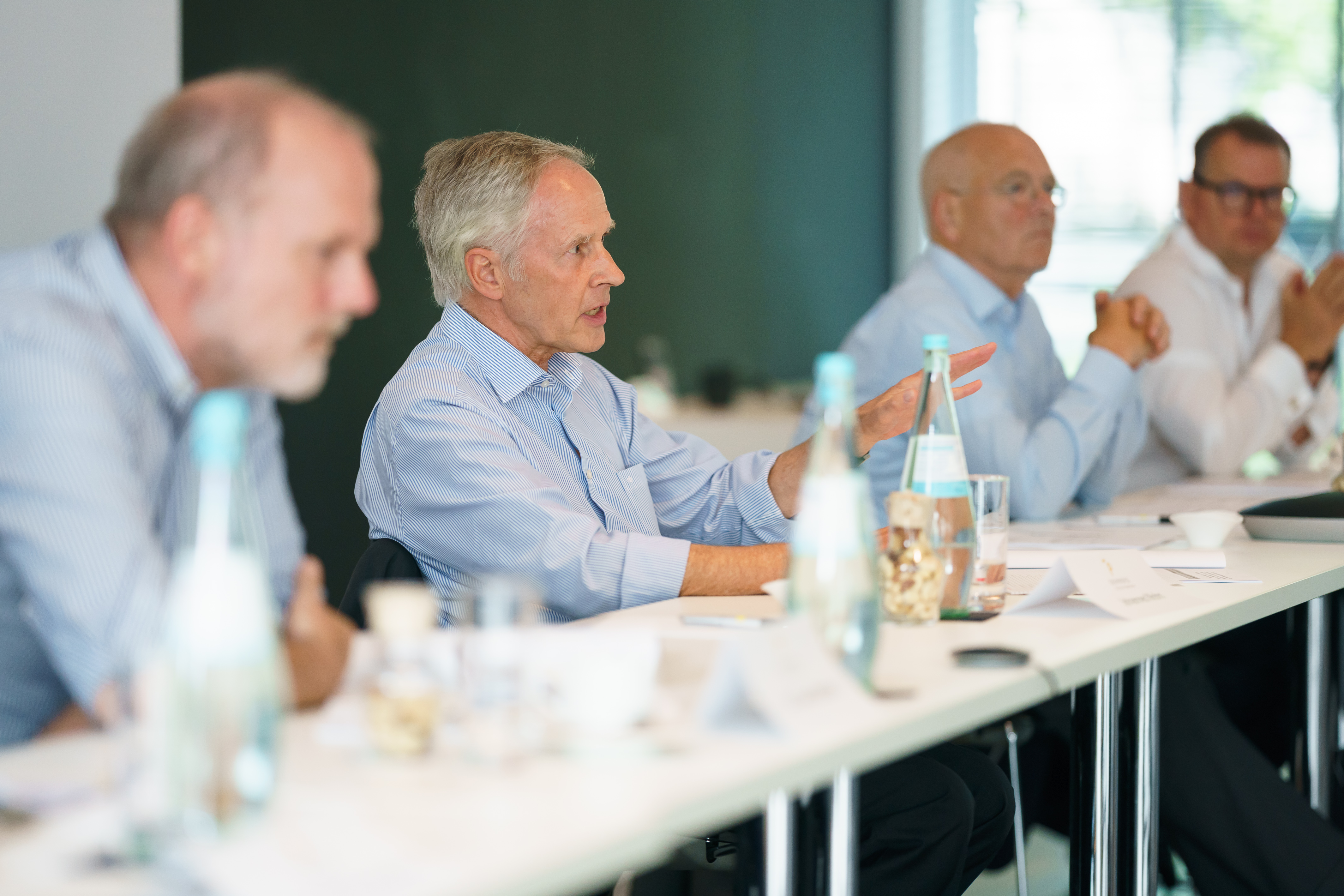 Four men in business attire in discussion at a conference table