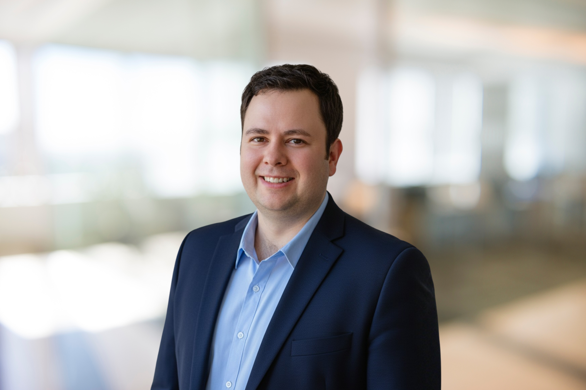 Portrait of a smiling man in a dark jacket in a bright office