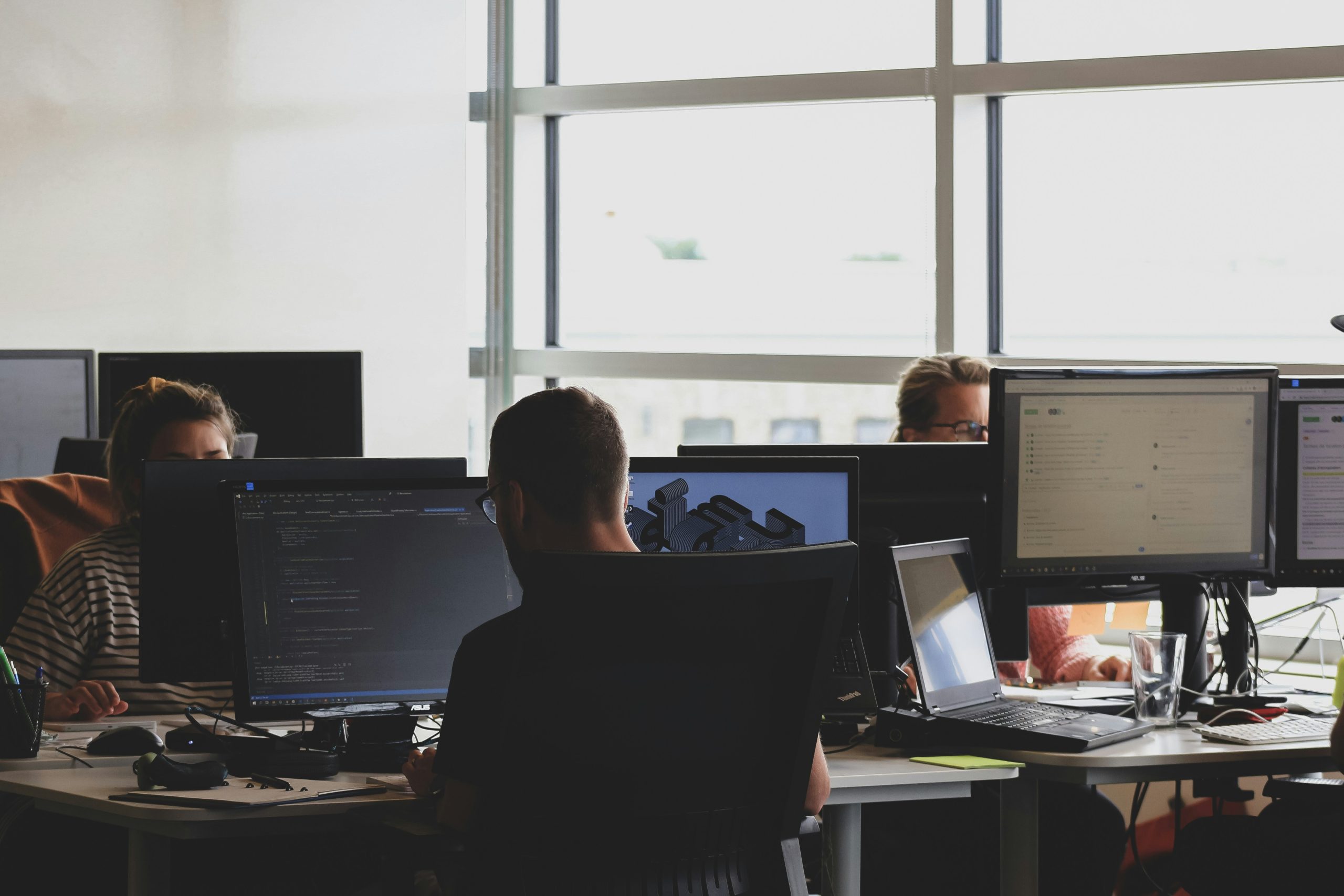 People working at several screens in a bright open-plan office