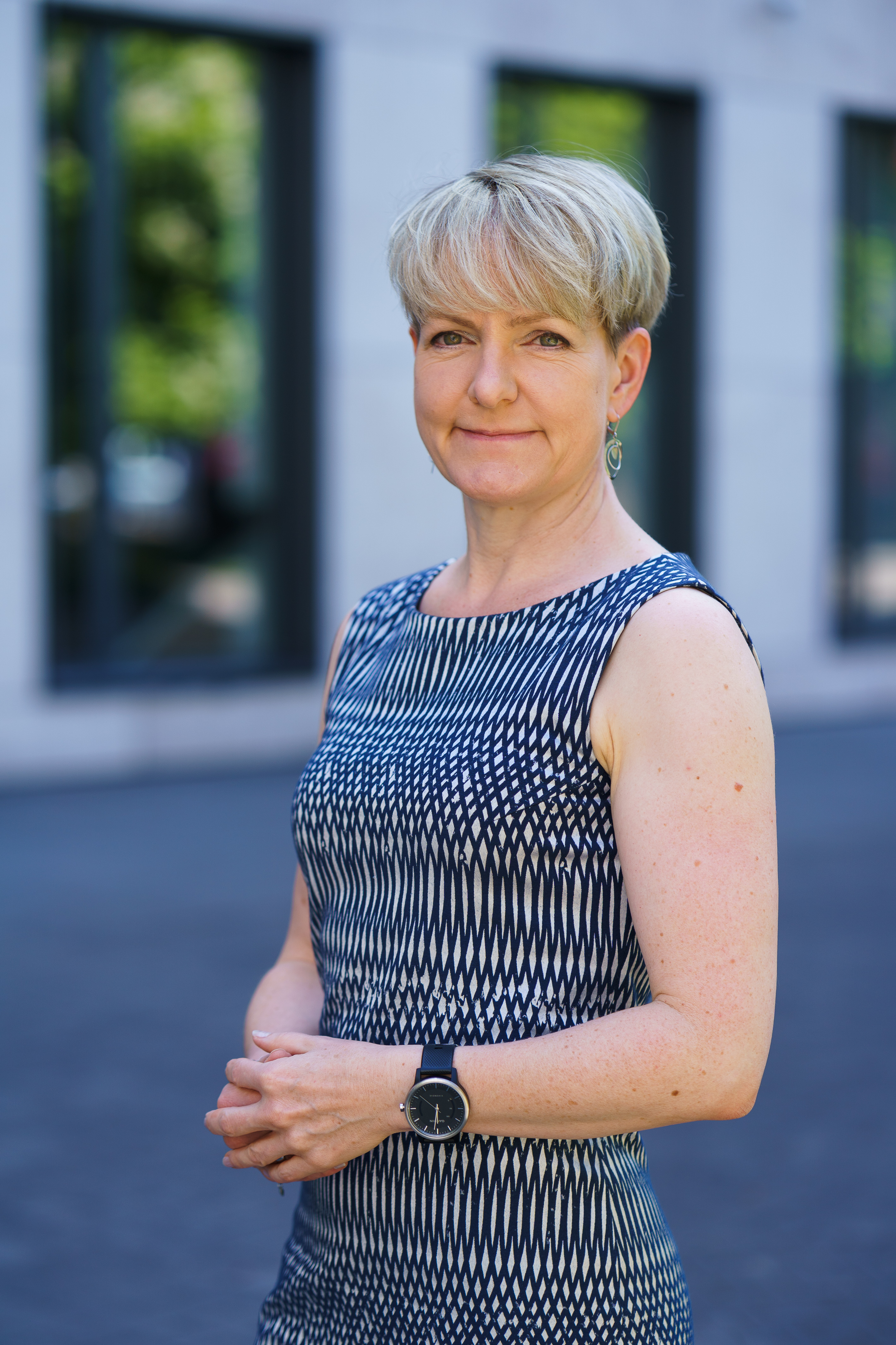 Portrait of a woman with short blonde hair in front of an office building