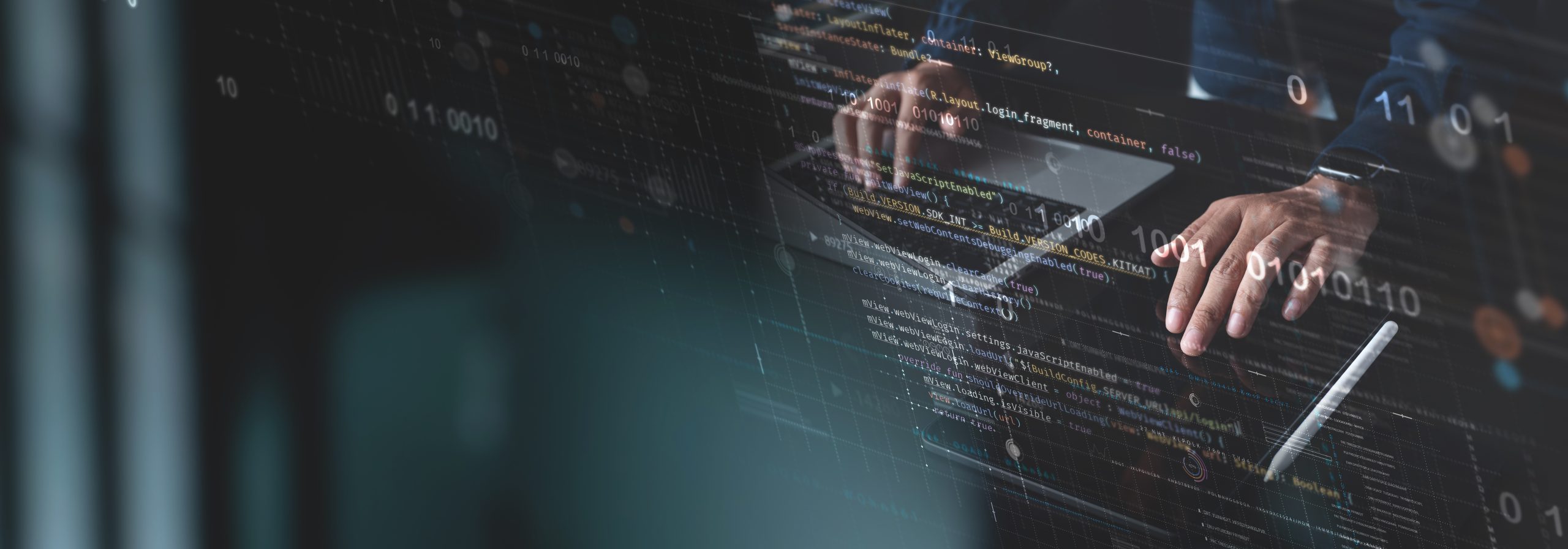 Hands on a keyboard in front of a screen showing program code
