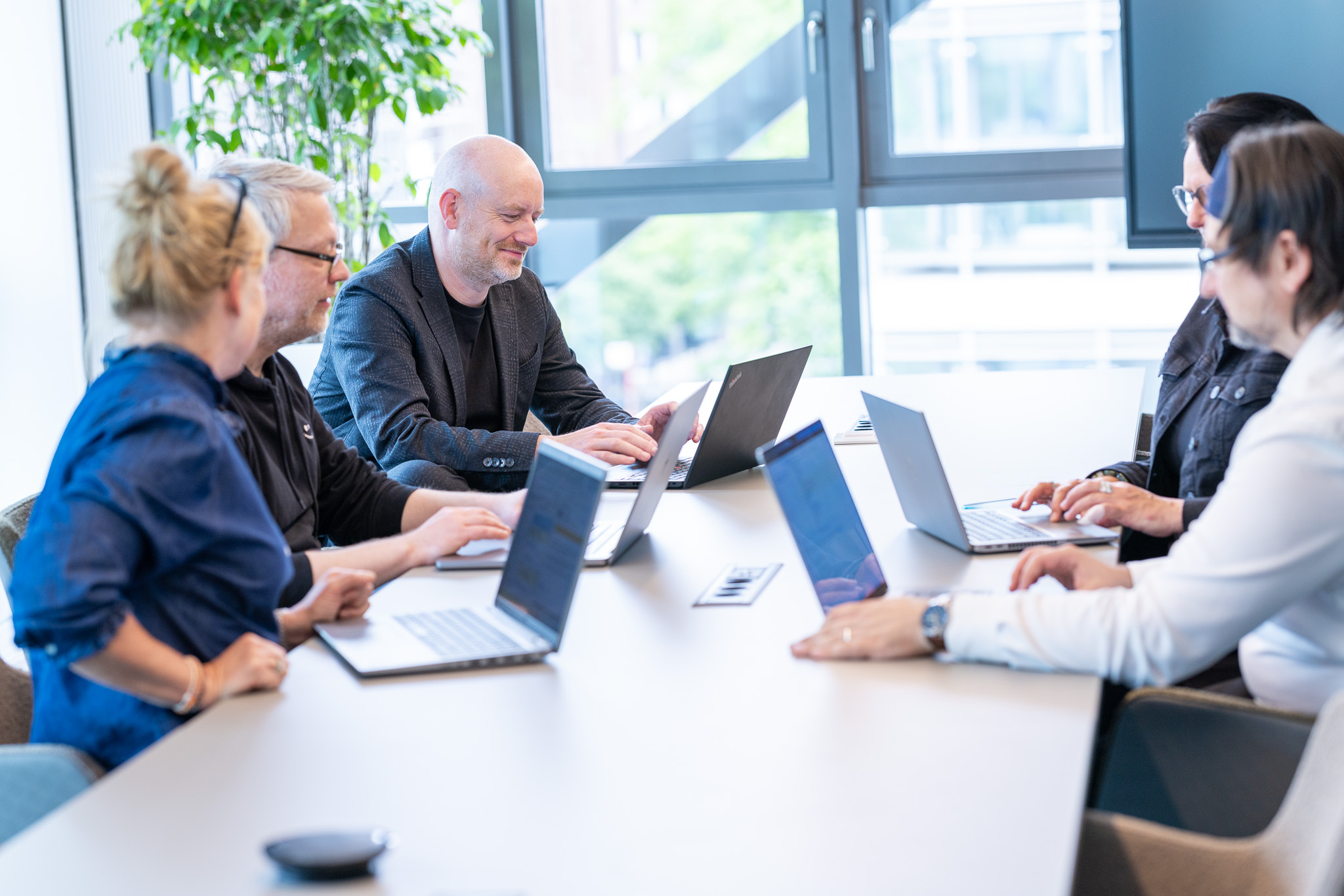 Four people talking at a table with laptops
