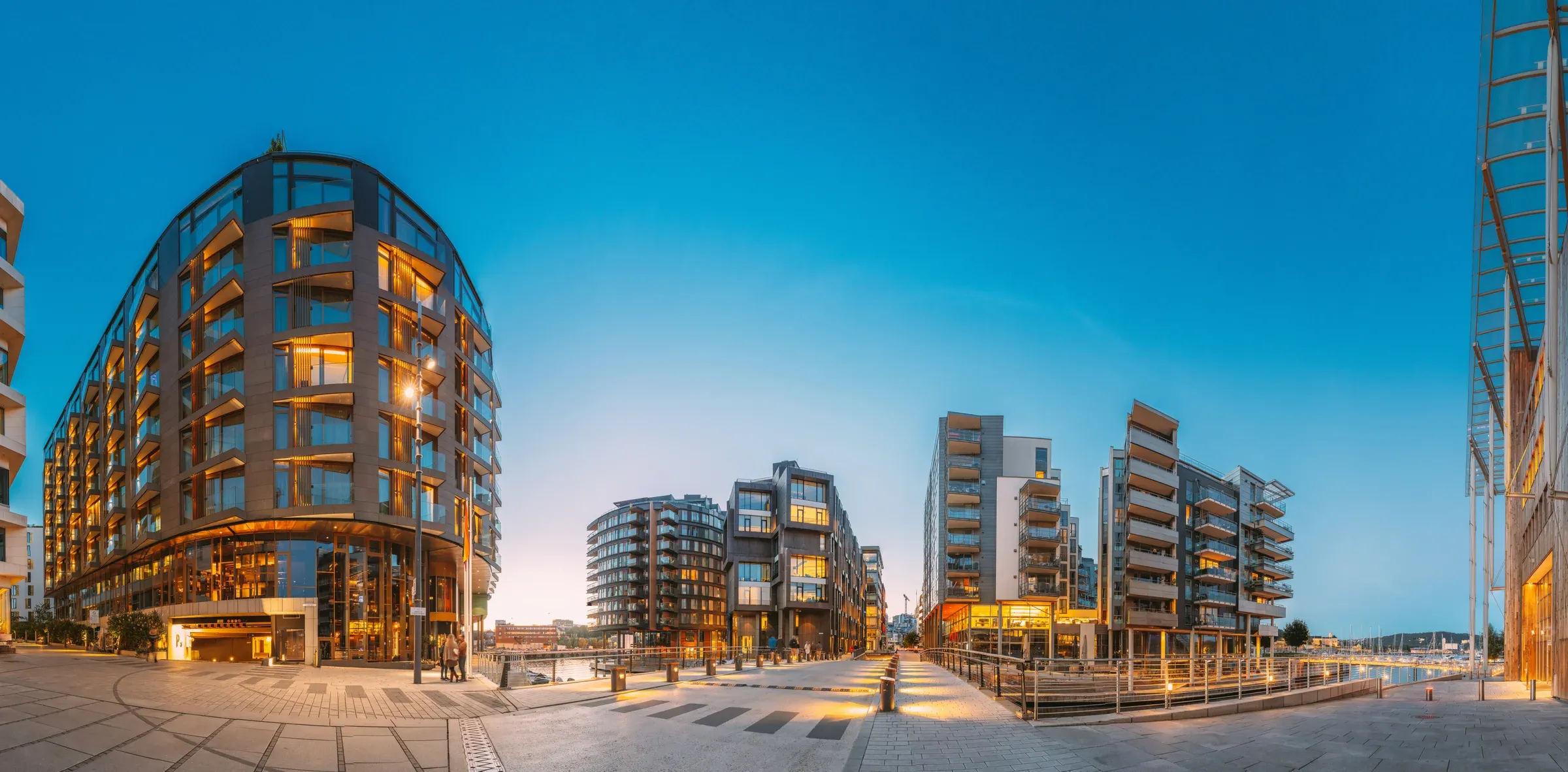 Harbour promenade with illuminated residential buildings at dusk